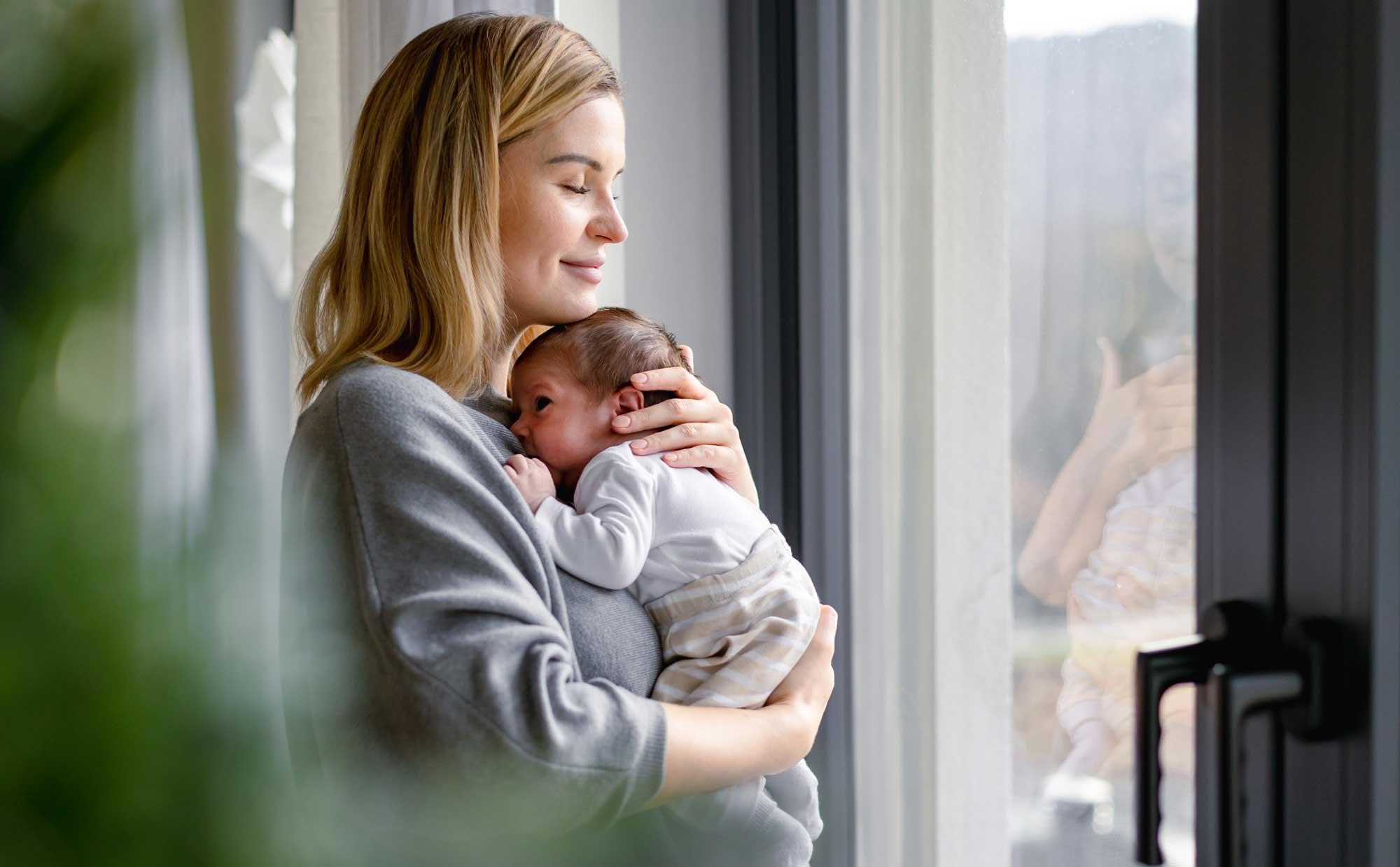 Loving Mother Hugs Her Little Baby at Home